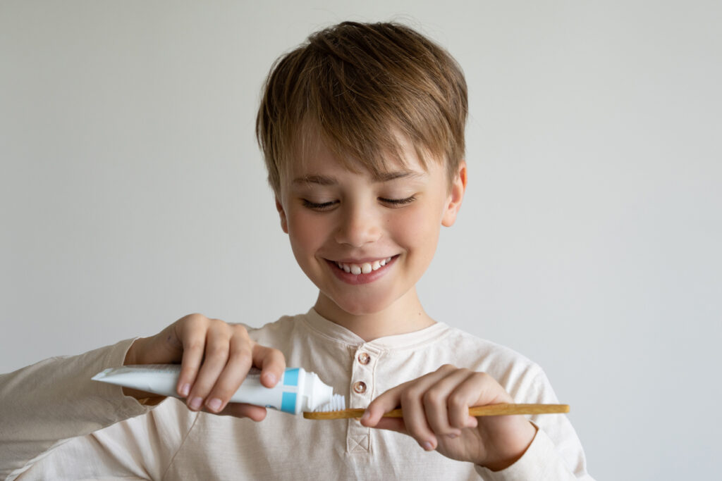 un enfant met du dentifrice sur une brosse à dents